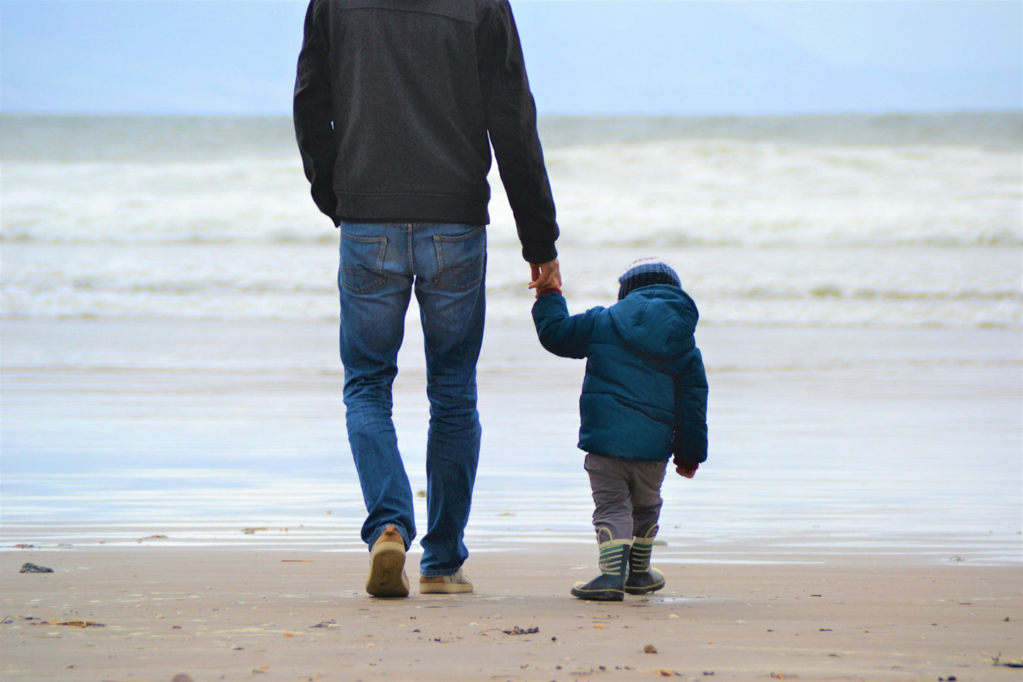 Father and son walking hand in hand on a beach, symbolizing vitality, strength, and the importance of testosterone boosters for men’s overall health and energy.
