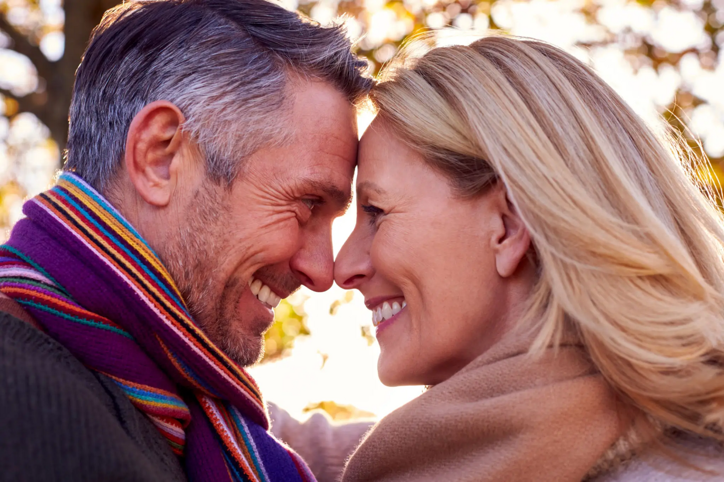 Middle-aged couple smiling warmly with foreheads touching outdoors in fall, representing emotional closeness, renewed intimacy, and romantic connection after successful erectile dysfunction treatment with Clutch’s doctor-prescribed sildenafil for men over 40.