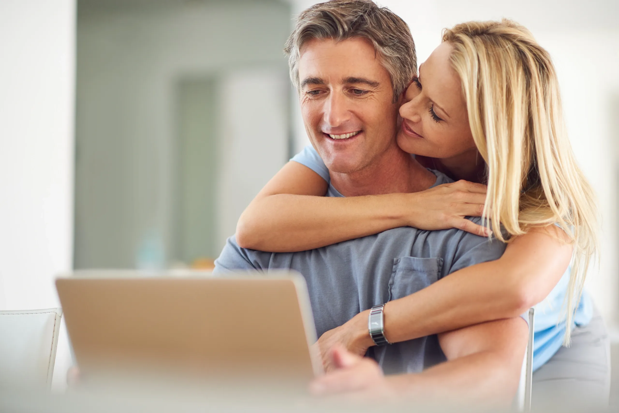 Man and woman hugging and looking at a laptop together as a happy couple after increasing stiffness hardness and duration of going longer in bed delaying climax with edging and buying generic sildenafil 100mg online for ED solution.