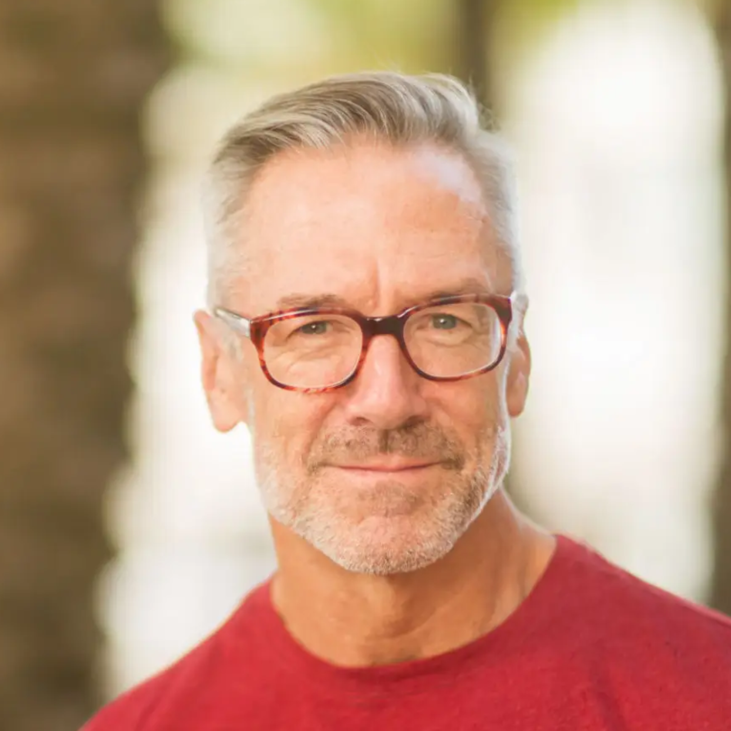 Forty Health client wearing glasses and a red shirt standing outdoors with trees in the background for testimonial of hair loss shampoo successful outcomes buying prescription strength and regaining hair, to show benefits of testosterone for men.