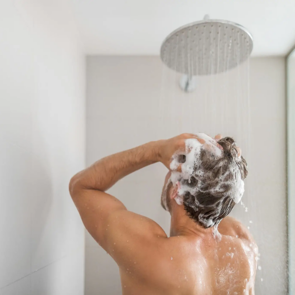 Man washing his hair with best shampoo for hair thinning 2025, promoting hair regrowth and scalp health using Fortify RX Shampoo with finasteride, minoxidil, and progesterone for effective treatment of thinning hair.