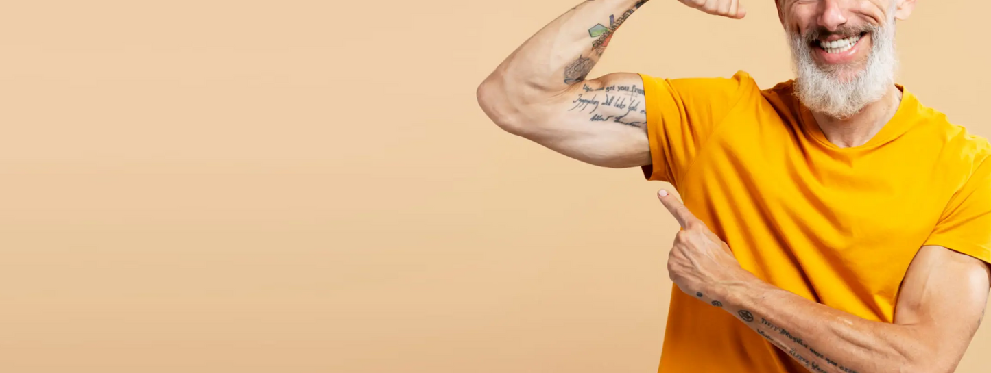 Smiling older man with a beard flexing his bicep and pointing to it, symbolizing vitality and strength after Forty Health’s testosterone replacement therapy TRT enclomiphene HRT and men’s health solutions.